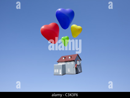 Herzförmige Luftballons und Miniaturhaus Stockfoto