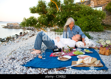 Älteres Paar mit Picknick am Strand Stockfoto