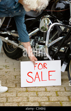 Mann, der für Verkaufsschild mit dem Oldtimer Motorrad Stockfoto