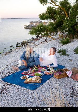 Älteres Paar mit Picknick am Strand Stockfoto