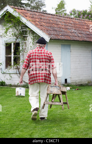 Älterer Mann Malerei seinem Sommerhaus, Schweden. Stockfoto