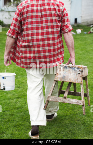 Älterer Mann Malerei seinem Sommerhaus, Schweden. Stockfoto