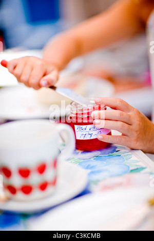 Mädchen, die Marmelade aus Flasche mit Messer, Nahaufnahme Stockfoto