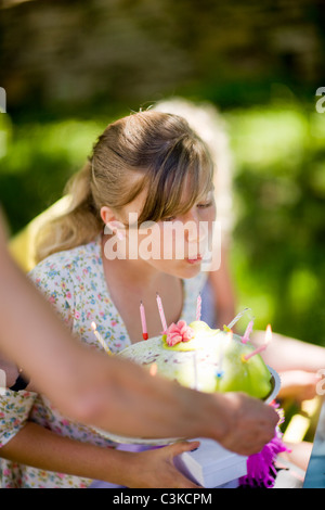 Mädchen bläst Kerzen auf Geburtstagskuchen Stockfoto