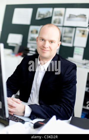 Mann sitzt im Büro, Lächeln Stockfoto