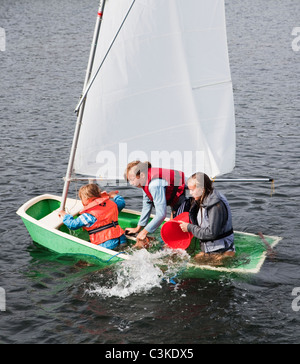 Drei Mädchen, die Entfernung von Wasser aus Schlauchboot Stockfoto