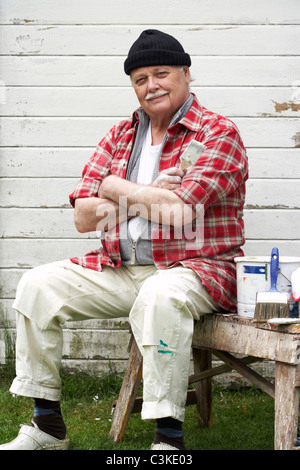 Älterer Mann Malerei seinem Sommerhaus, Schweden. Stockfoto