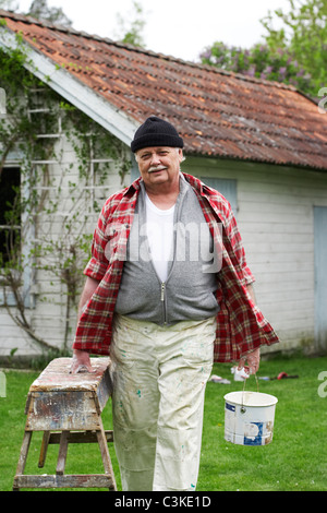 Älterer Mann Malerei seinem Sommerhaus, Schweden. Stockfoto