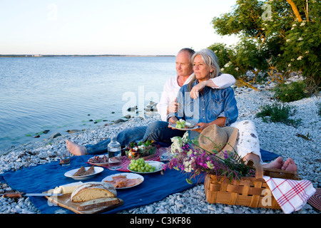 Älteres Paar mit Picknick am Strand Stockfoto