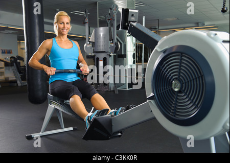 Frau im Ruderer im Fitness-Studio trainieren Stockfoto