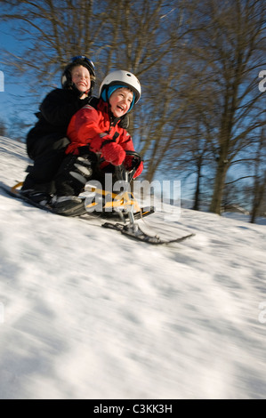 Jungen und Mädchen auf Schnee Rodeln Stockfoto