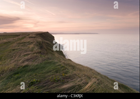 Schöner roter Sonnenuntergang über Filey Brigg - Sonnenuntergang über Küstenklippenpfad, hohe Sandsteinklippen & ruhiges Meer - North Yorkshire Coast, England, UK. Stockfoto