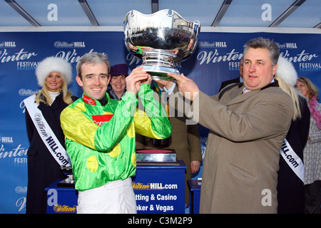 Ruby Walsh und Paul Nicholls heben die Trophäe nach einer vierten Sieg in Folge König George VI in Kempton Park Racecourse. Stockfoto