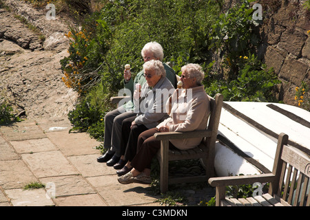 Drei ältere Frauen sitzen auf einer Bank, Eis essen, in der Fischerei Dorf Staithes, North Yorkshire, UK Stockfoto