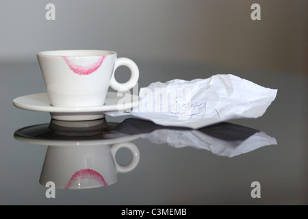 Lippenstift auf Espressotasse zusammen mit einem Zettel markieren "sorry". Spiegelt sich in glänzender Oberfläche Stockfoto