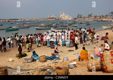 Indische Frauen versammeln sich um das Fischerboot bringt in seinen Fang in Vizhinjam Hafen in der Nähe von Kovalam, Kerala, Indien Stockfoto