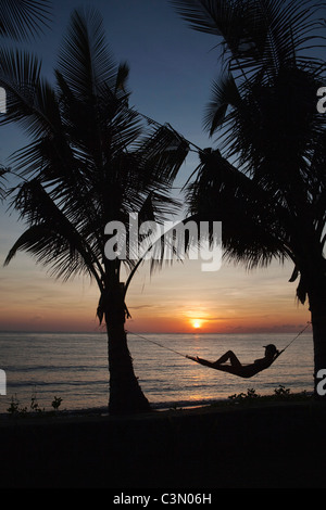 Indonesien, Insel Bali, in der Nähe von Tejakula Dorf, Gaia Oasis Resort. Frauen, Tourist, entspannen in der Hängematte bei Sonnenaufgang. Stockfoto