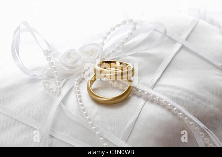 Trauringe auf Kissen vor weißem Hintergrund Stockfoto