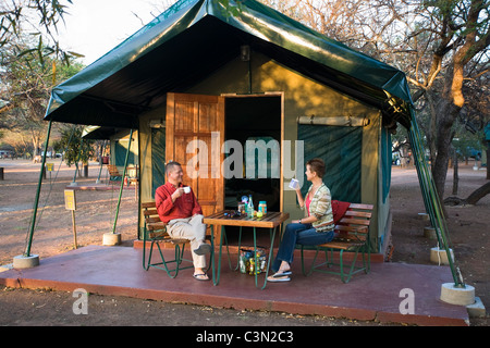 Südafrika, Pilanesberg National Park paar, Mann und Frau, frühstücken vor Safari-Zelt auf Campingplatz Stockfoto