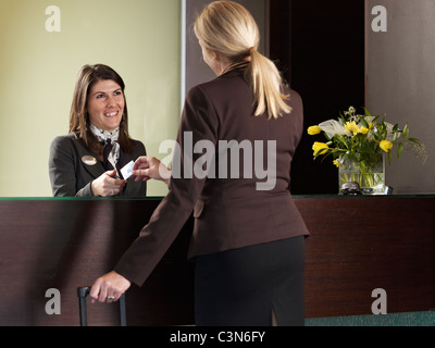 Geschäftsfrau, die Zahlung für ihr Hotelzimmer an der Rezeption Stockfoto