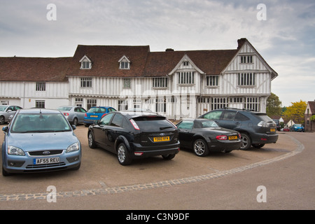 Moderne Autos geparkt vor einem mittelalterlichen Gebäude in Lavenham, Suffolk Stockfoto