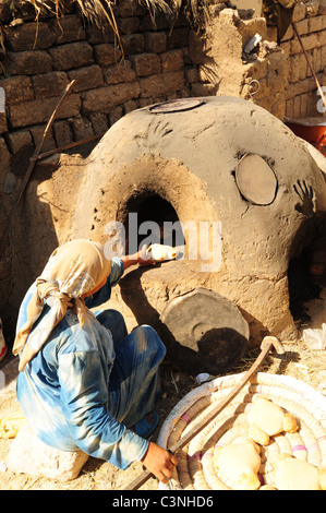 Afrika Naher Osten Ägypten Ägypterin Brotbacken in einem irdenen Ofen außerhalb bei ihrem ländlichen Bauernhof-Haus Stockfoto