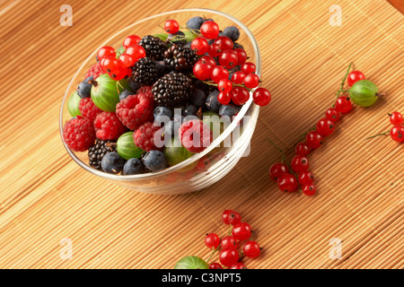 Obst-Mix in den Glasbehälter auf einem Tisch aus Stroh Stockfoto