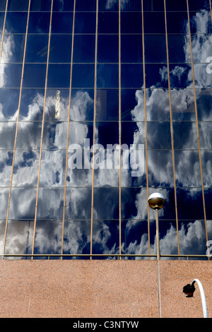 Wolken im tiefblauen Himmel spiegelt sich in Fenstern des Hochhauses Stockfoto