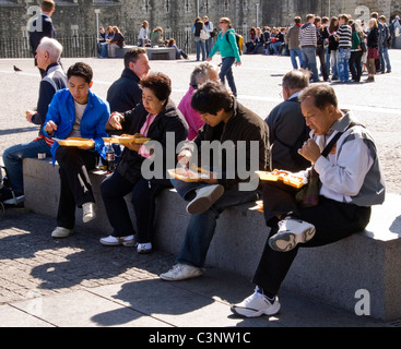 Asiatische Touristen Essen Speisen zum Mitnehmen an der Tower of London, London, England, UK Stockfoto
