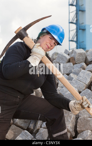 Weibliche Arbeiterin in schützende Kleidung mit Spitzhacke Stockfoto