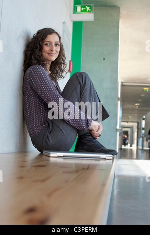 Deutschland, Leipzig, junge Frau sitzt mit Laptop, Lächeln, Porträt Stockfoto