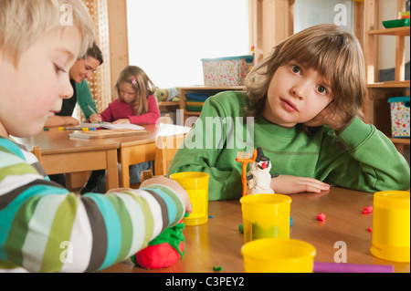 Deutschland, Kinder Kindergarten, weibliche Kindergärtnerin im Hintergrund Stockfoto