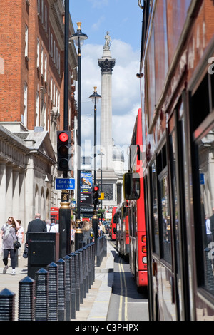 London, Westminster, Trafalgar Square, Nelsons Column von Whitehall durch rote Doppeldecker & Verkehr gesehen leuchtet Stockfoto