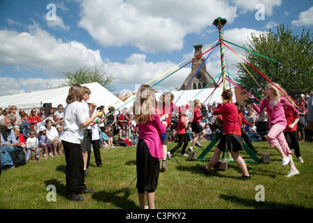 Kinder aus einer örtlichen Grundschule Tanz runden den Maibaum am Maifeiertag zu erreichen Fair, Reach, Cambridgeshire, Großbritannien Stockfoto