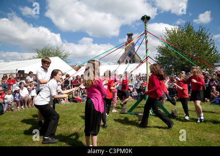 Kinder aus einer örtlichen Grundschule Tanz runden den Maibaum am Maifeiertag zu erreichen Fair, Reach, Cambridgeshire, Großbritannien Stockfoto