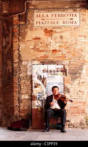 Im mittleren Alter Straßenmusikant in Anzug spielt eine Violine für Geld in Venedig, Venetien, Italien Stockfoto