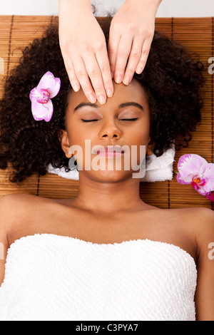 Brasilianische Frau im DaySpa, Handauflegen Bambus Massage-Tisch mit Kopf auf Kissen tragen ein Handtuch bekommen eine Gesichtsmassage. Stockfoto