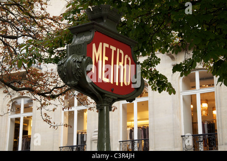 Ein Wahrzeichen der Pariser Métro-Kunst im Jugendstil. Im Hintergrund sind die eleganten Fenster eines gehobenen Geschäfts in der Champs Elysées zu sehen. Paris, Frankreich. Stockfoto