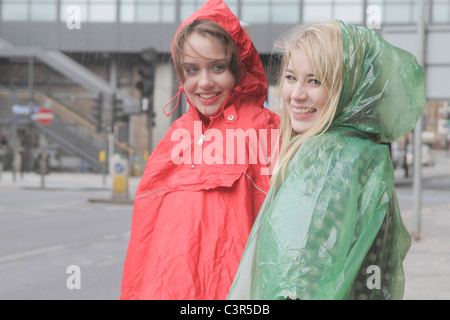 2 junge Frauen in Regenmäntel in der Stadt Stockfoto