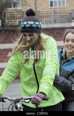 2 junge Frauen auf 1 Push bike Stockfoto