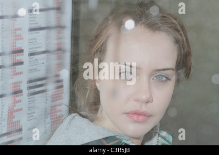 Junge Frau am Bushäuschen in Regen Stockfoto