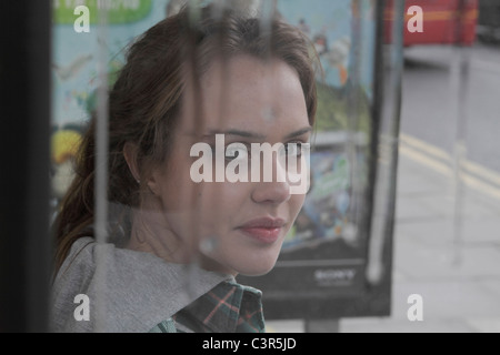 Junge Frau am Bushäuschen in Regen Stockfoto