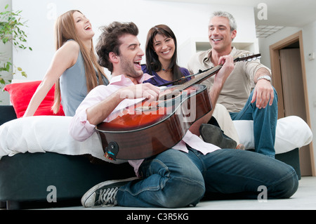 Fröhliche Freunde singen und spielen Gitarre Stockfoto