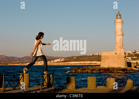 Frau balancieren auf Steinen vor einem Leuchtturm Stockfoto