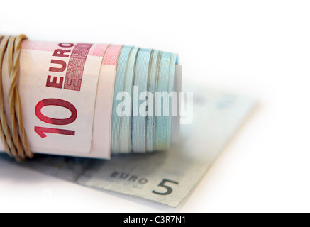 einem elastischen Band um einen aufgerollten Bündel von 10 und 20 Euro-Banknoten - alles auf einen 5 Euro-Schein Stockfoto