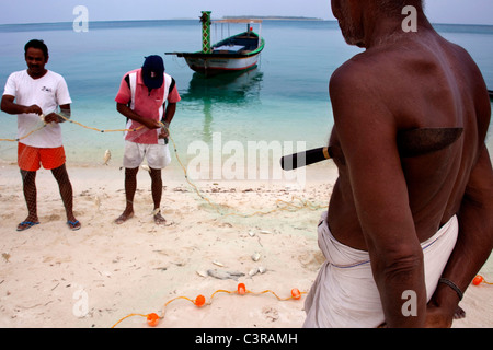 Fischer und Boot, Männer mit Fischernetz am Strand, Lakkadiven, Lakshadweep, Indien Stockfoto