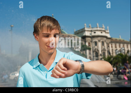 Deutschland, München, Karlsplatz, junger Mann überprüfen der Zeit Stockfoto