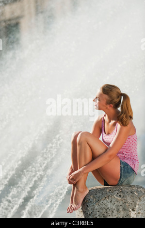 Deutschland, München, Karlsplatz, junge Frau am Brunnen sitzen Stockfoto