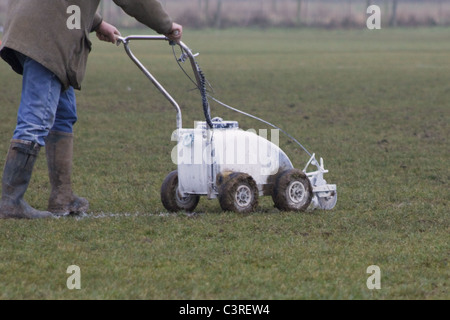 Platzwart Malerei weiße Linien auf Fußballplatz mit einem Push entlang Maschine Stockfoto