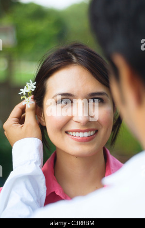 Hispanic Mann setzen Blume hinter Frau Ohr Stockfoto